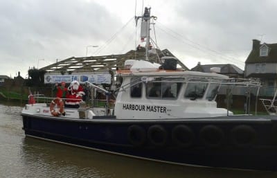 He's here! Father Christmas and his helper arrive in style on the Harbour Master's launch