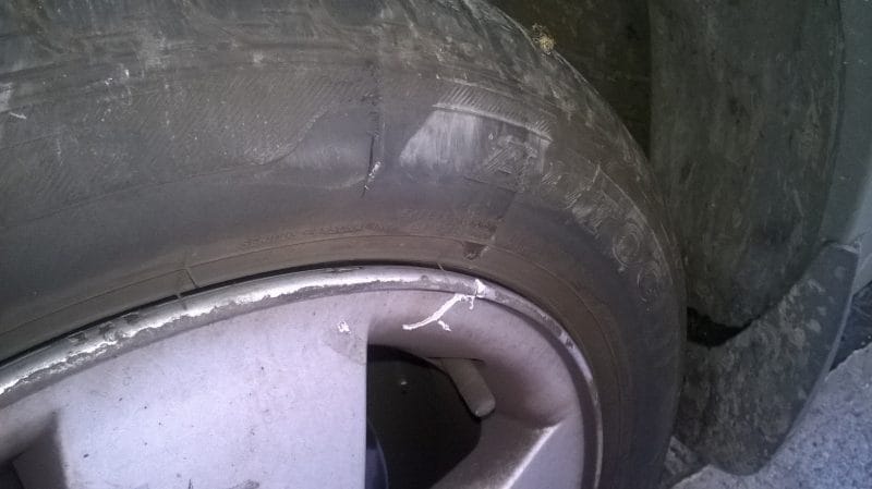Tire slashed by corner jutting out beyond pavement